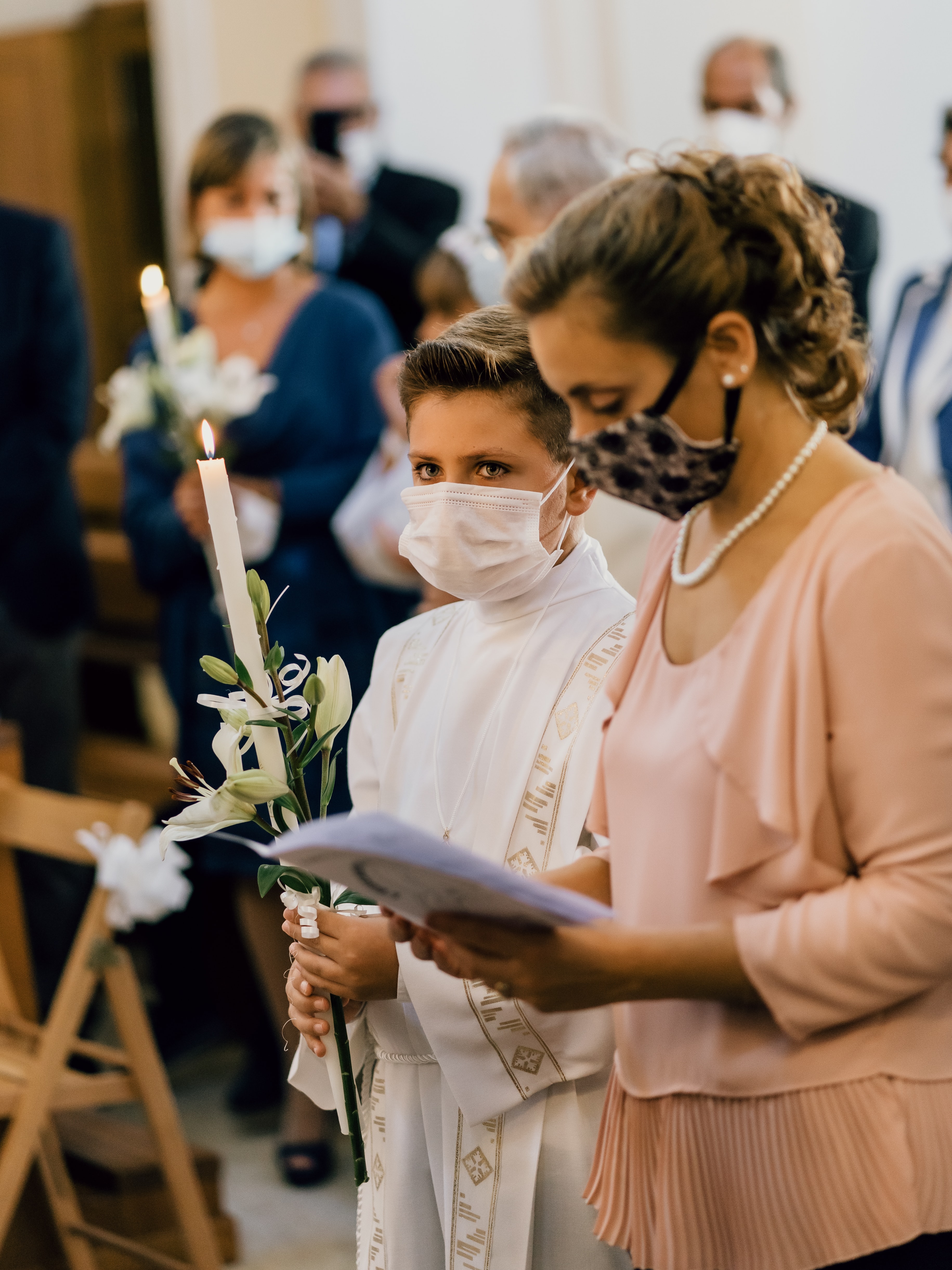 A woman and altar boy wearing masks in a church