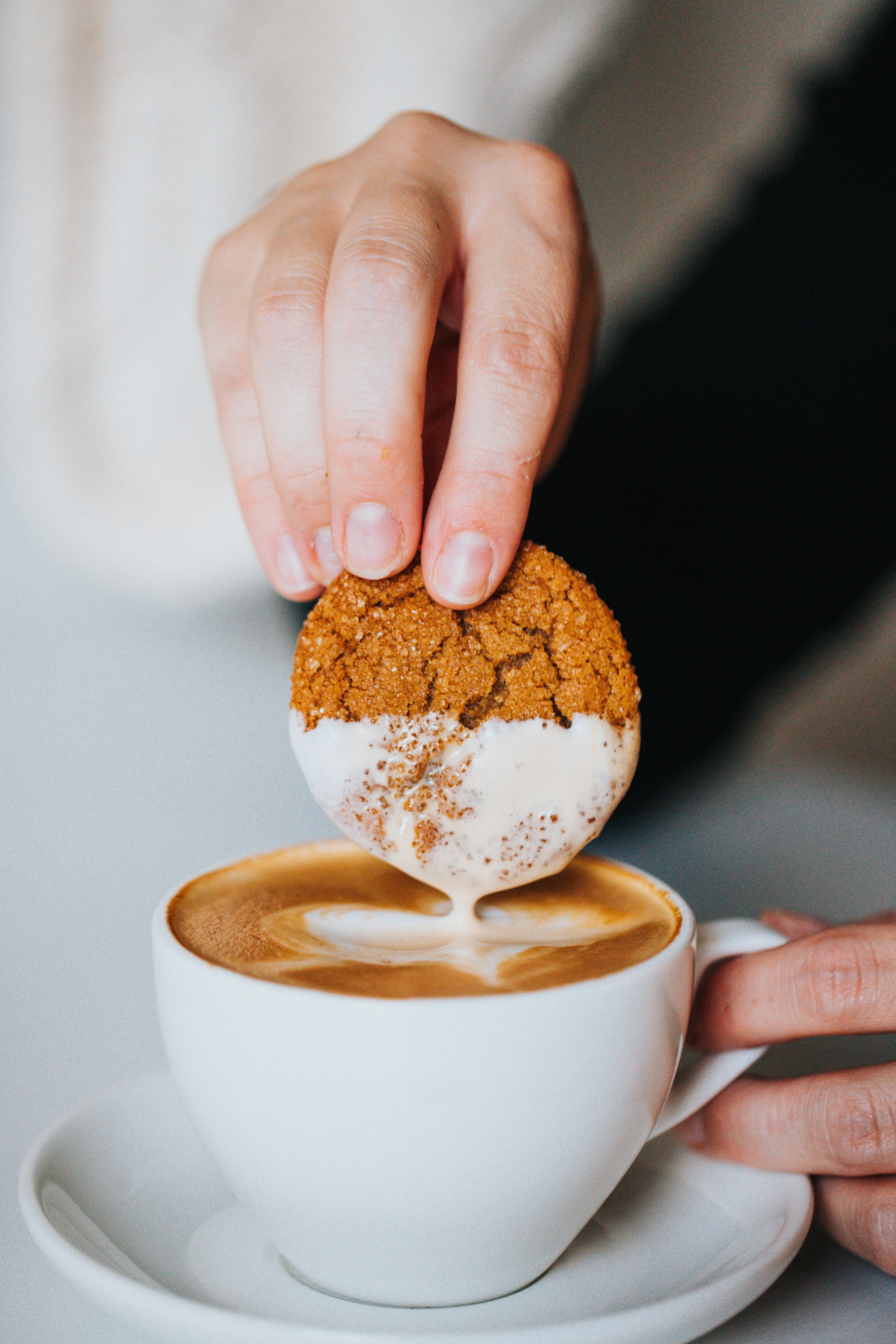 Person dipping cookie into cup of coffee